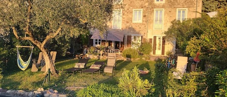 A stone building with a pool, outdoor seating, and a hammock.
