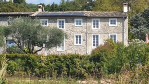 A stone building with multiple windows and a tiled roof, surrounded by greenery and trees. - Rustico at south shore of Lake Garda (Costermano)