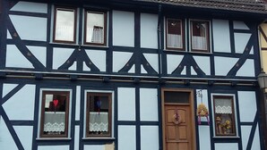 Una casa tradicional con entramado de madera, una puerta de madera, varias ventanas y un cimiento de piedra.