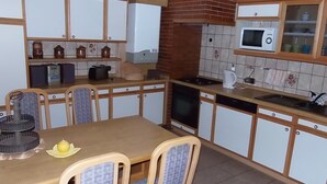 Una cocina con armarios de madera, microondas, estufa y una mesa de comedor con sillas.