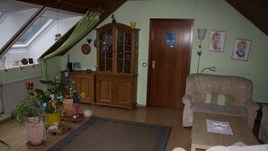 A cozy living room with a wooden cabinet, a sofa, a coffee table, and a large window with a view of the sky. - Cozy holiday apartment in Kirchlengern in a quiet residential area (Kirchlengern)