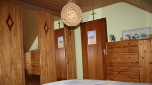 A bedroom with wooden wardrobes, a bed with a quilt, and a hanging light fixture. - Cozy holiday apartment in Kirchlengern in a quiet residential area (Kirchlengern)