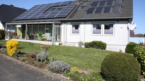 A house with solar panels on the roof, a well-maintained lawn, and a satellite dish. - Cozy holiday apartment in Kirchlengern in a quiet residential area (Kirchlengern)