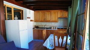 Una cocina compacta con armarios de madera, un refrigerador y un comedor con mesa y sillas.