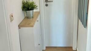 A hallway with a white door, a small plant on a shelf, and a radiator on the wall. - Daub's island oasis/apartment with terrace also possible with dog (Borkum)