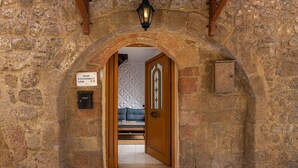 Una entrada con un arco de piedra, una puerta de madera y un cartel con el número de la habitación.