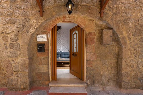 An entrance with a stone archway, a wooden door, and a sign indicating the room number.