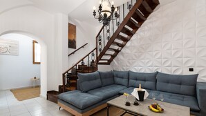 Una sala de estar moderna con un sofá seccional, una mesa de centro y una escalera con un diseño geométrico en la pared.