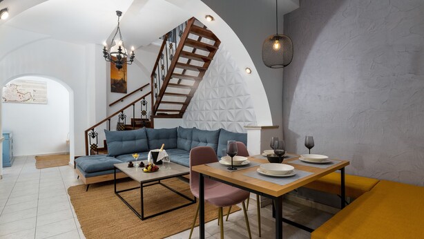 Una sala de estar moderna con una escalera, una zona de comedor y un sofá.