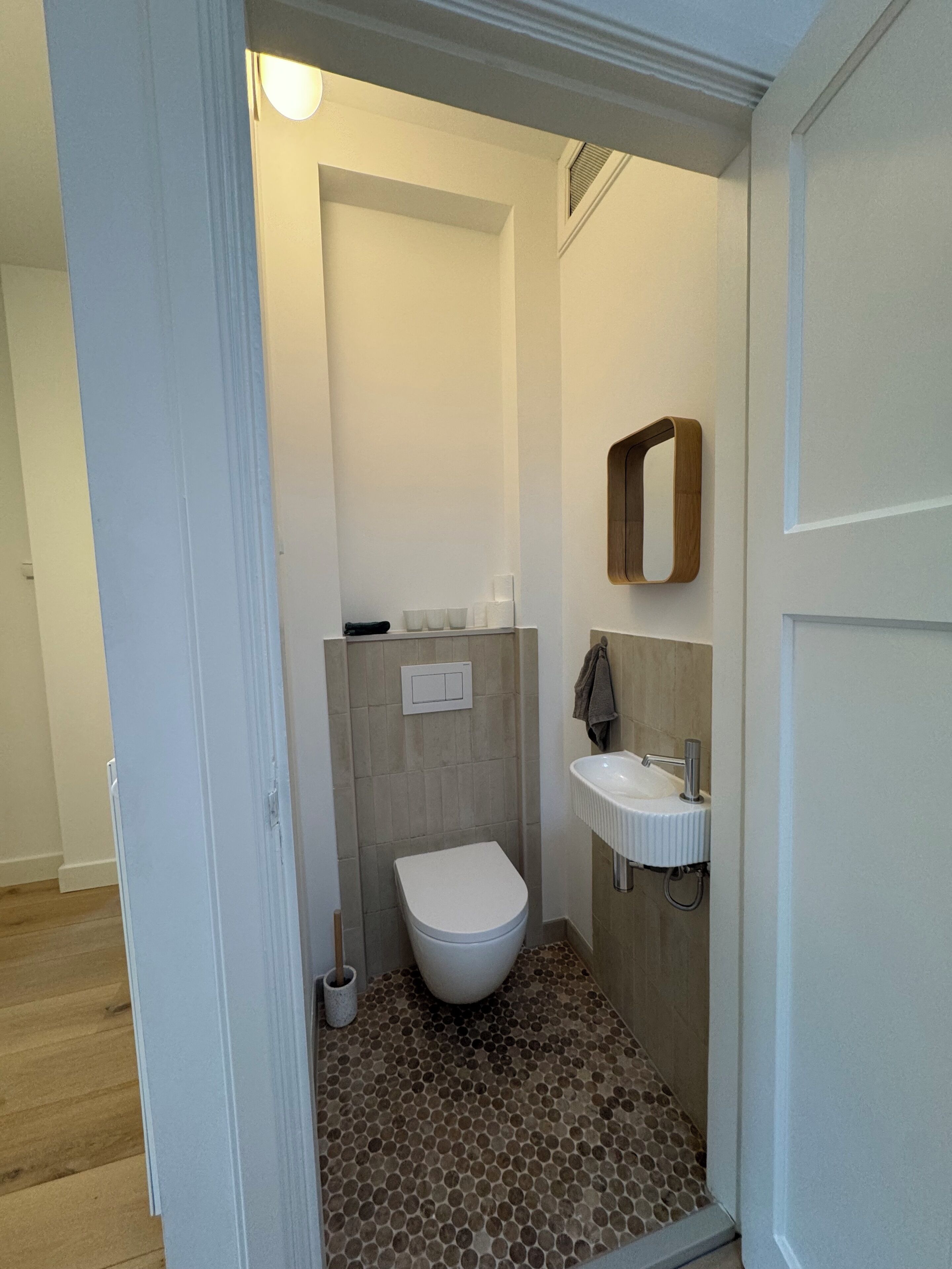 A modern bathroom with a toilet, sink, and mirror.