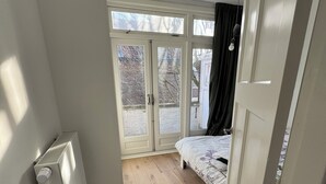Un dormitorio con cama, radiador, ventana y puerta.