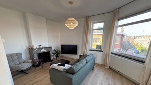 Una sala de estar con sofá, sillón, televisión, chimenea y vistas a la ciudad.