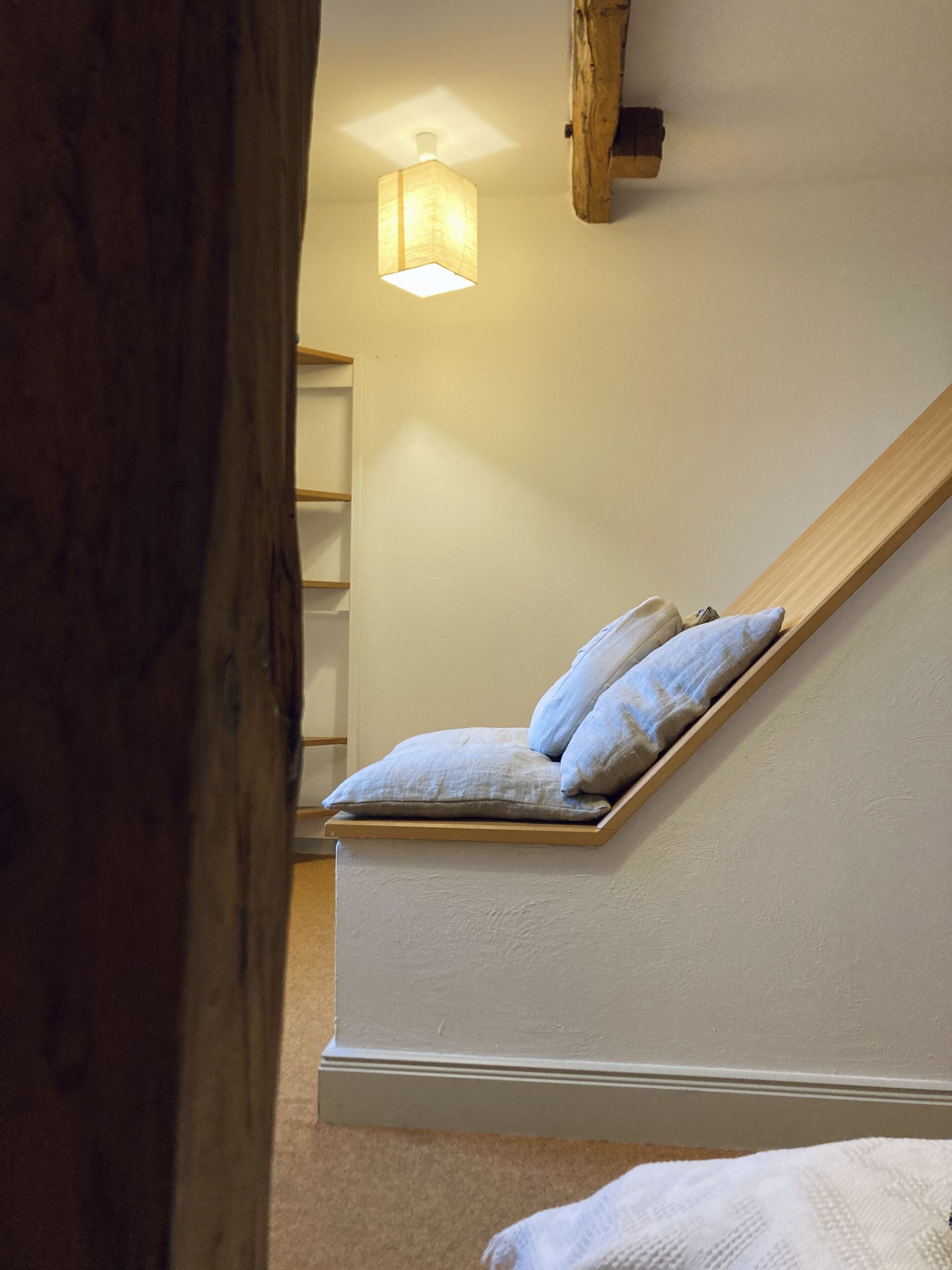 Ein Schlafzimmer mit Holzbalkendecke, einem Bett mit Kissen und einem Nachttisch.