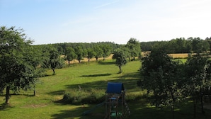 Un'area giochi con uno scivolo e una struttura per arrampicarsi, circondata da alberi e prato.