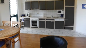 Una cucina compatta con angolo pranzo, dotata di pensili, forno a microonde, lavello e macchina del caffè.