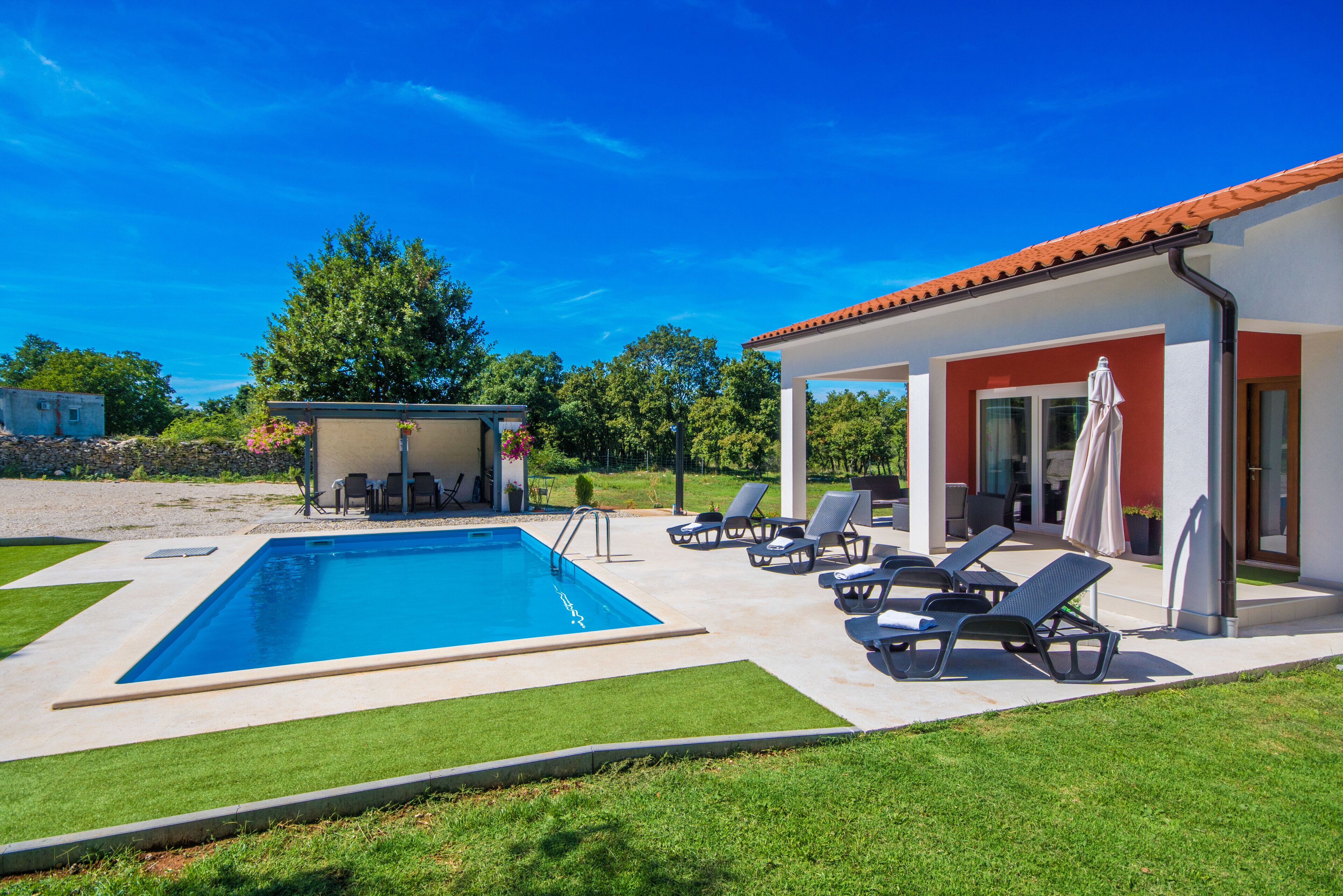 A swimming pool with lounge chairs and a covered patio area.