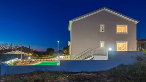 Une maison moderne à deux étages, dotée d’une piscine, d’un patio couvert et d’un escalier menant à l’étage supérieur.