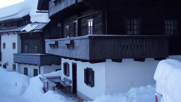 Un edificio de madera tradicional con techo nevado y varios balcones.