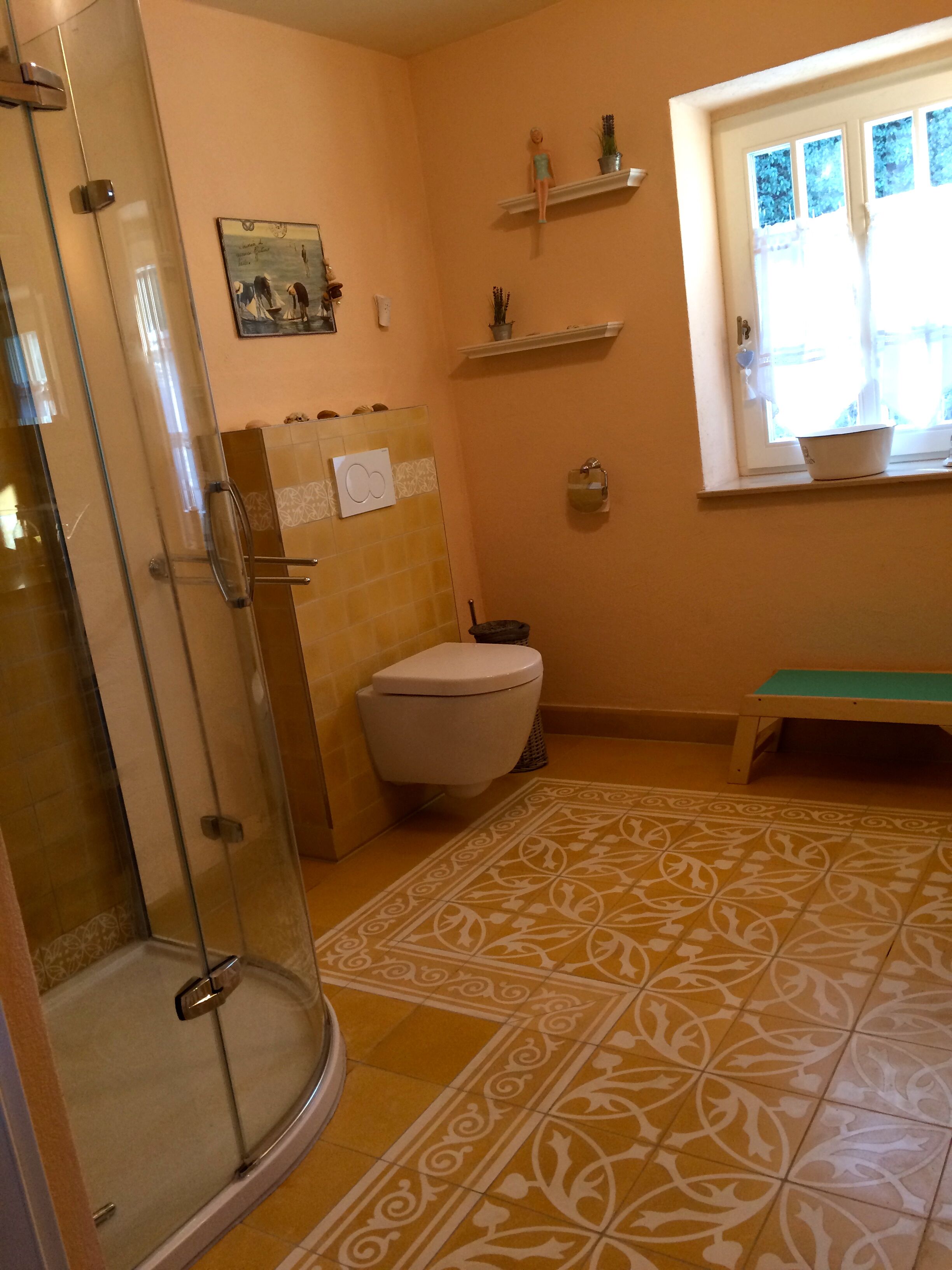 A bathroom with a glass shower enclosure, a toilet, a sink, and a window with a view of trees.