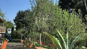 A wooden deck with potted plants, a striped table, and a pair of sunglasses on the table. - large family friendly holiday home with terrace and garden close to the old town (Görlitz)