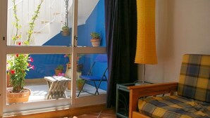 Une pièce dotée d’une porte-fenêtre coulissante donnant sur un balcon agrémenté de plantes en pot et d’une chaise bleue.