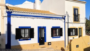 Un bâtiment à deux étages, doté d’une façade blanche, de cadres de fenêtres bleus et d’une base jaune.