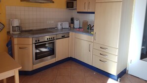 A kitchen with a stove, oven, microwave, and cabinets. - Darss-Wieck, living room-kitchen-bedroom-balcony, sauna, 2- 3 persons, bicycle shed (Wieck)
