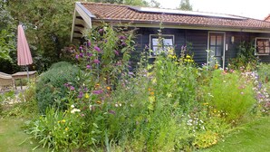 A house surrounded by a garden with various flowers and plants. - Cozy "Schwedenhaus" with a beautiful view, located on the water (Idsegahuizum)