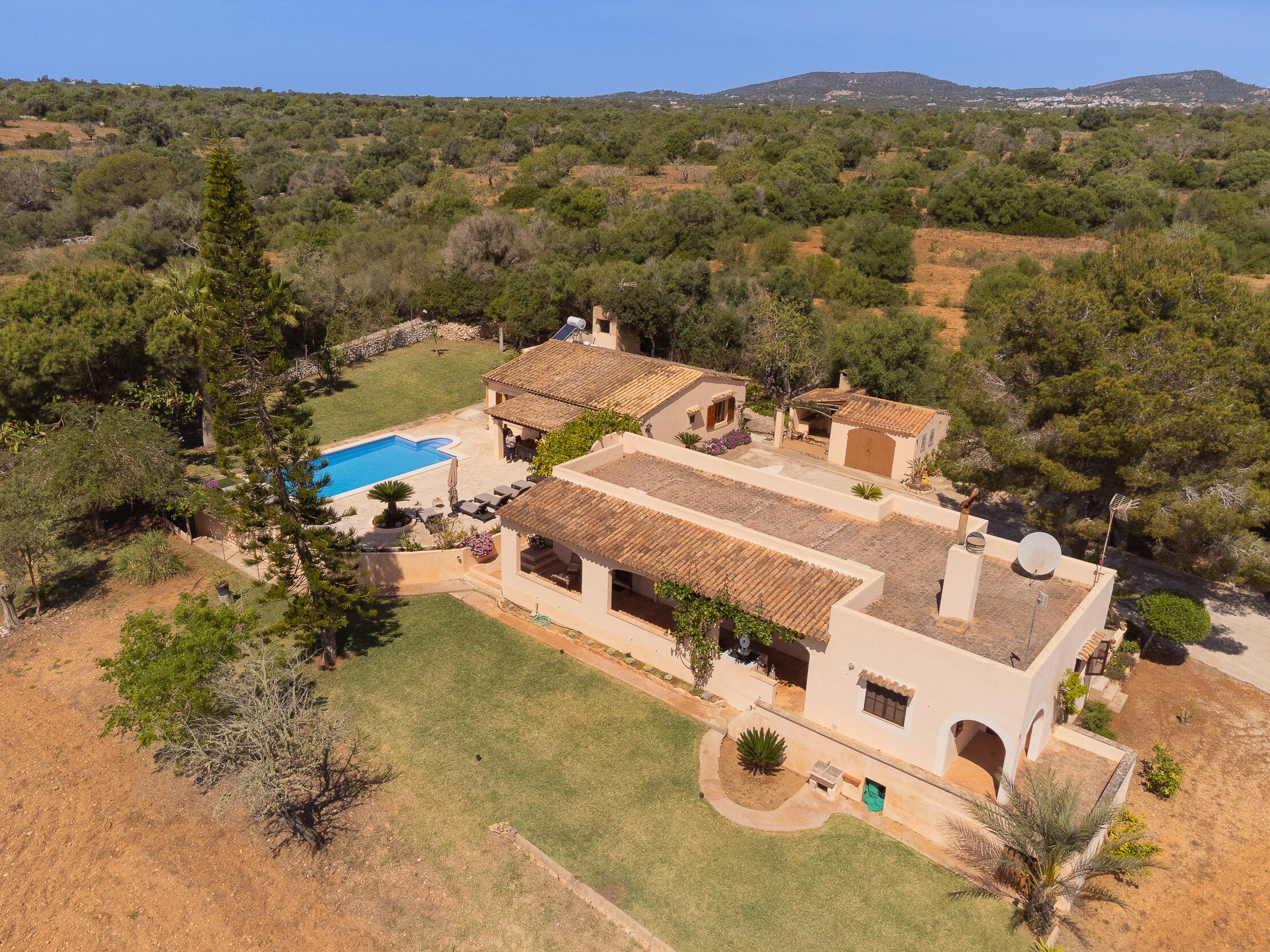 Eine mediterrane Villa mit Swimmingpool, Terrakotta-Dach und üppiger Bepflanzung.