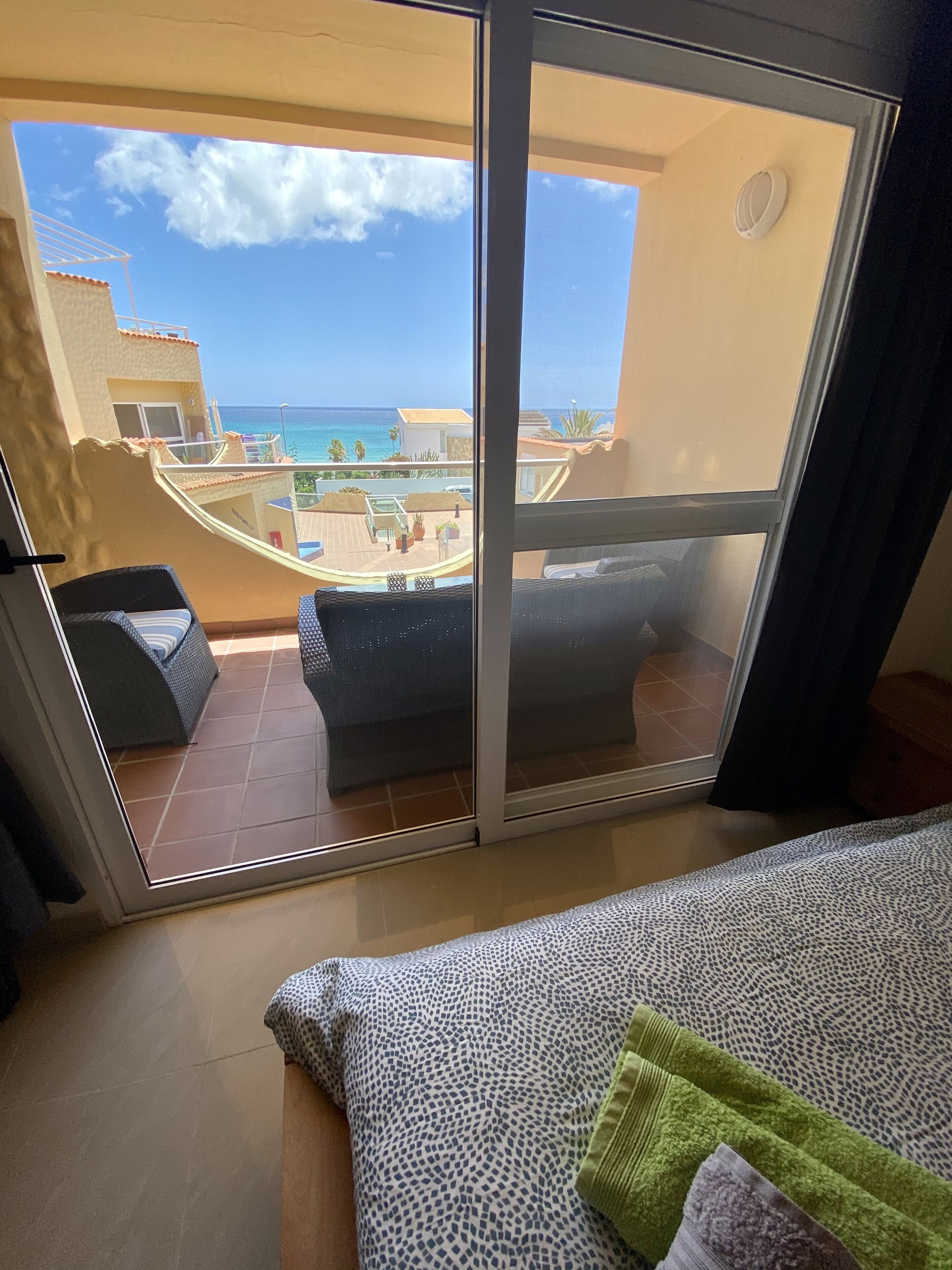 A balcony with a view of the sea and a pool area.