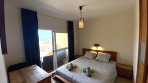 Un dormitorio con cama, una mesita de noche, una lámpara colgante y vistas al exterior.