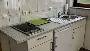 Een keuken met witte kastjes, een roestvrijstalen spoelbak en een groen snijplank.