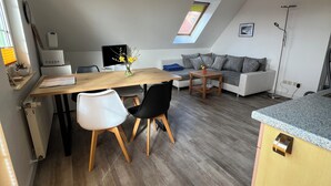 Un appartement moderne de style « loft », comprenant un coin repas, un canapé, une petite table et une fenêtre de toit.