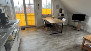Une cuisine moderne avec un coin repas, un téléviseur et une vue par les fenêtres.