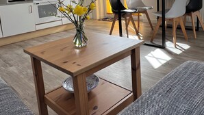 Une cuisine moderne avec des meubles blancs, une table à manger en bois et un vase rempli de fleurs jaunes.