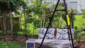 Un patio con un columpio, una mesa redonda y un banco de madera.