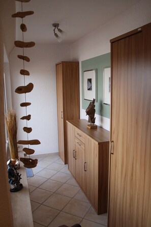 A hallway with wooden cabinets, a wall-mounted sculpture, and a tiled floor.