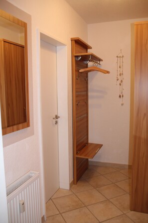 A hallway with a wooden wardrobe, a radiator, and a hanging light fixture.