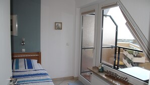 Et soveværelse med seng, vindue med udsigt, radiator og et sengebord.