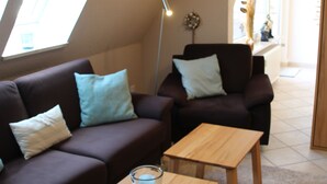 En moderne stue med en brun sofa, to træsideborde og en glaskandeholder.
