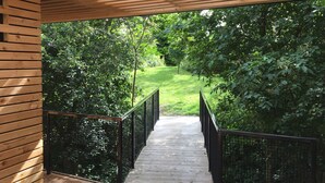 A wooden deck with a metal railing leading to a lush green garden.