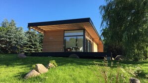 A modern house with a sloped roof, large windows, and a wooden exterior.