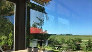 A modern room with a large window offering a view of a green landscape and a red structure.
