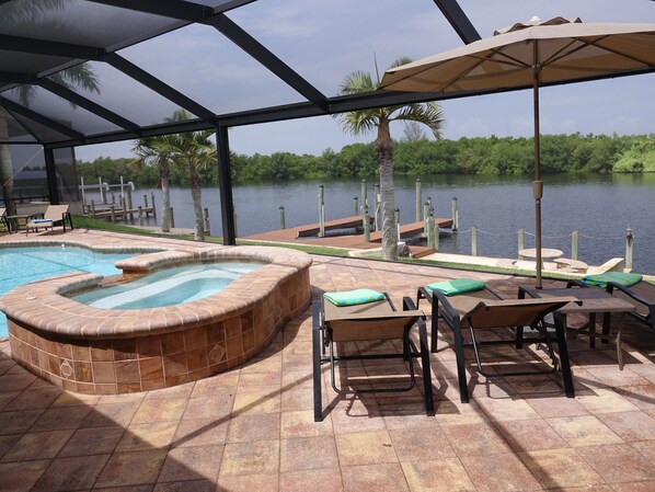 Un espace piscine doté d’un jacuzzi, de chaises longues et offrant une vue sur un lac.