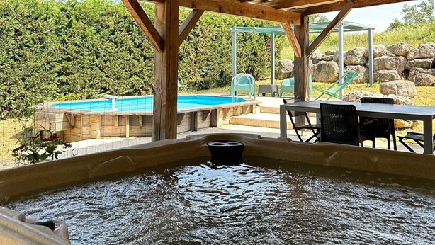 A hot tub under a wooden pergola with a pool in the background. - the gites les chênes n. 2, private pool and spa (Servas Gard)