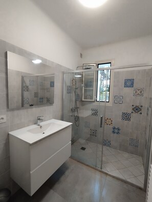 A bathroom with a white sink, a glass-enclosed shower, and patterned tiles on the walls. - Villa for 8/10 people, 10 minutes' walk from the beach, air-conditioned. Quiet neighborhood. (L'île-Rousse)