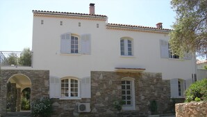 A two-story building with a stone facade, white shutters, and a tiled roof.