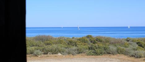 A coastal landscape with a clear view of the sea and distant sailboats.