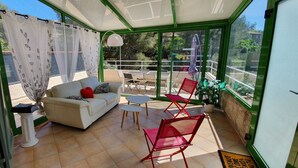 Eine sonnendurchflutete Terrasse mit einer Couch, Stühlen und einem Tisch.