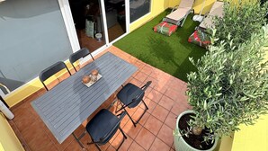 A patio with a table and chairs, a covered area with a sliding door, and a small lawn. - Cozy apartment in a well-kept complex with pool, only 40 meters to the beach (Corralejo)